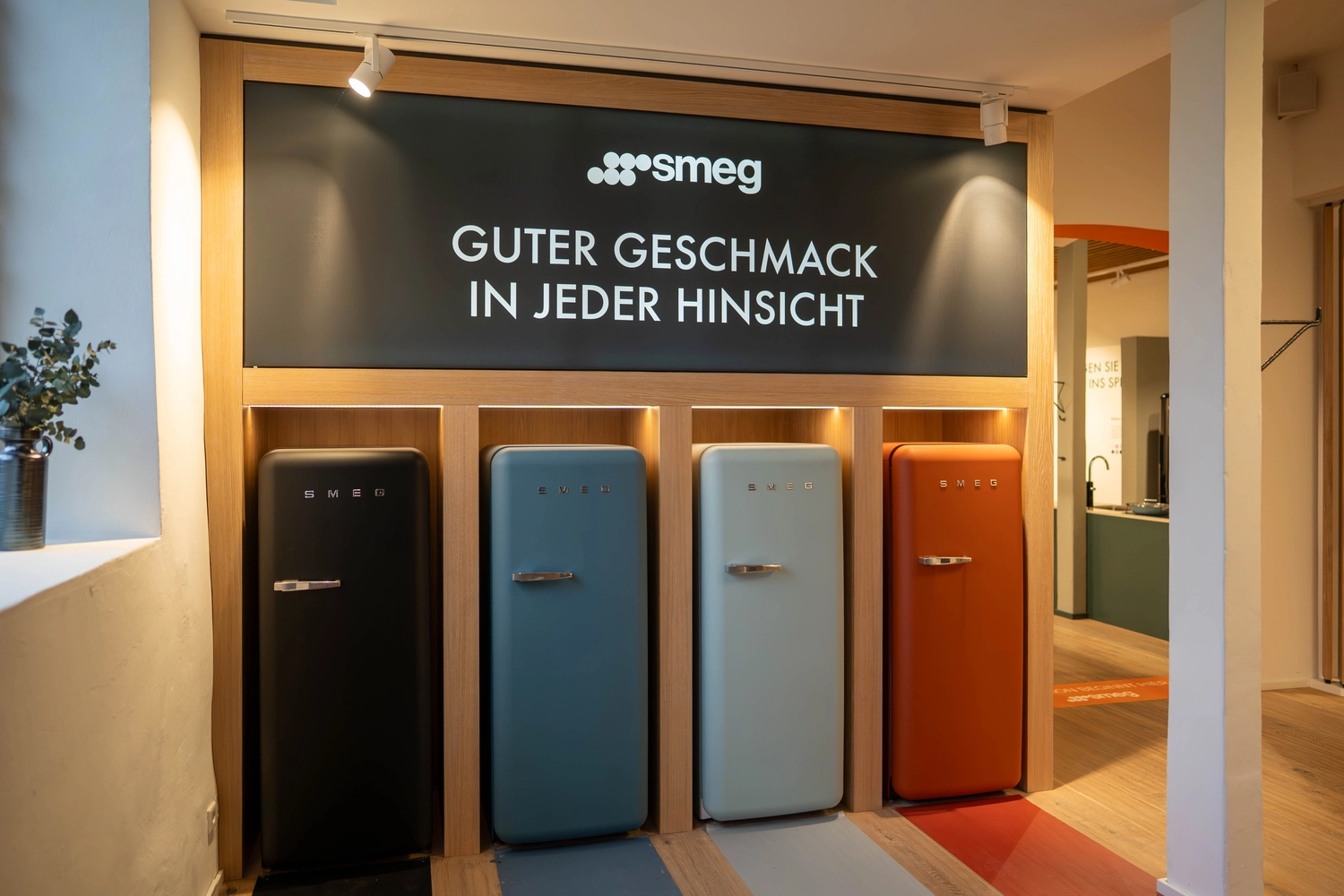 Heinrich Buchholz – Holzbearbeitung – Eine elegante, minimalistische Verkaufsfläche mit einer durchgehenden Akzentwand aus warmtonigem Holzfurnier, einer Sitzbank und passenden, schwebenden Produktregalen.